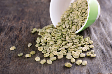Green coffee beans in a cup on wooden table