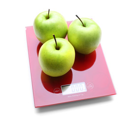 Three apples on digital kitchen scales, isolated on white