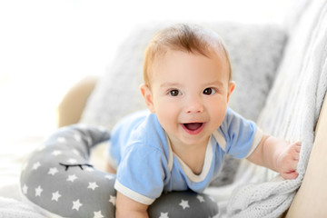 Fototapeta premium Little baby boy crawling on a couch at home