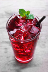 Glass of cherry soda with ice and fresh mint on rustic wooden background
