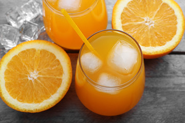 Glasses of orange juice with ice on rustic wooden background