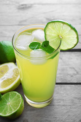 Glasses of lemon soda with ice and fresh mint on rustic wooden background