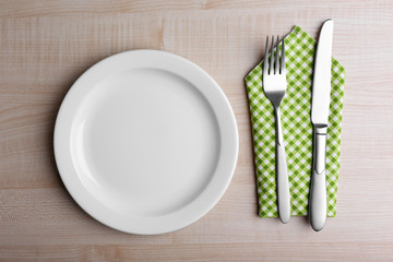 Empty plate with silver cutlery on wooden background