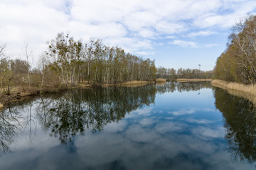 Spring at the lake. Reflection of clouds in water.