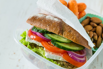 Vegan sandwich in lunch box with carrots and nuts