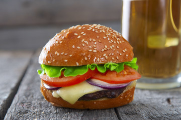 Fresh and juicy hamburger with a beer on wooden table.