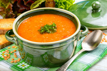 Red lentil cream soup on wooden table.