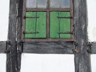 Grüne Fensterläden aus Holz in einer schönen alten Fachwerkfassade mit schwarzen Holzbalken im Bauernhausmuseum Bielefeld am Hermannsweg im Teutoburger Wald in Ostwestfalen-Lippe