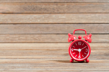 Red clock on wooden texture.