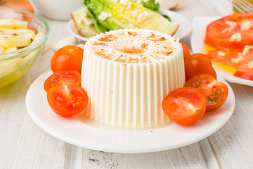piece of soft cheese with cherry tomatoes on wooden
