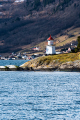 Fototapeta na wymiar Small lighthouse in Norwegian fjord. Vertical composition