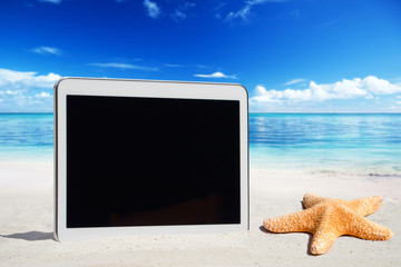 Weisses Tablet mit leerem Touchscreen Display steck im Sand am Meeresstrand