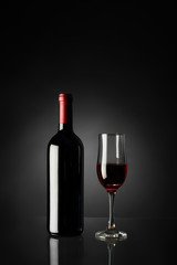 Glass of red wine and bottle on a black background