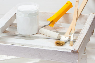 brushes and roller for painting wooden planks in white paint