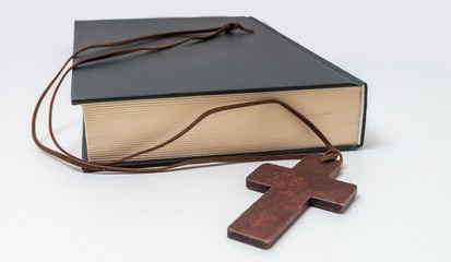Theology concept. Bible book and brown crucifix on necklace.