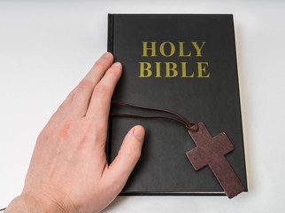 Religion concept. Hand touches Holy Bible.