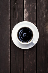 White coffee cup with black coffee on wood background, vertical style