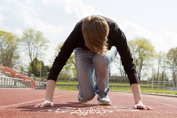 Young woman in casual clothes on a tartan track