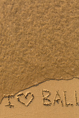 I love Bali - phrase written by hand on the beach with soft waves.