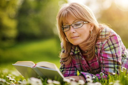 Attractive mature woman reading a book in the park