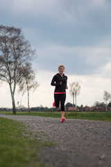 Hübsche Frau im Frühling, joggen auf einem Schotterweg