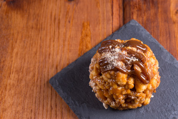Homemade dessert out of cakes and biscuit with caramel, chocolate and powdered sugar on stone slate plate on wooden background