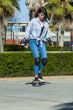 Beautiful young woman practicing with the skateboard on the stre