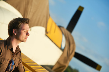 Outdoor fashion shot of male model posing with vintage old propeller plane