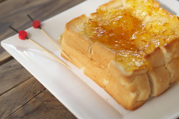 Toast with jam topping serve on a white dish.