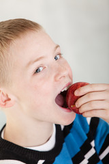 Cheerful boy biting into apple