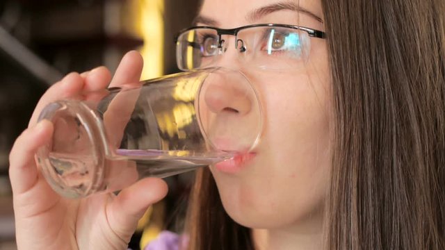 young woman drinks clear water from the glass