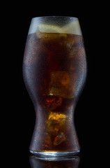 Coca-Cola with ice and lemon in a transparent glass on the black