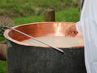 Fototapeta na wymiar cheesemaker checks with hand the milk's temperature inside the b