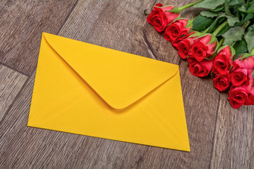 Yellow envelope and roses on a wooden background