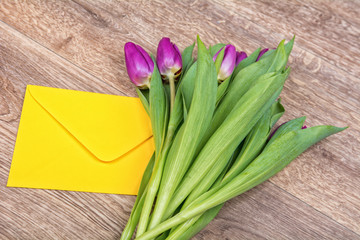 Envelope and tulips on a wooden background