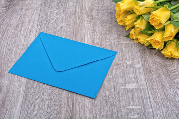 Blue envelope and roses on a wooden background