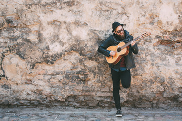 Hipster blond man playing guitar on the street