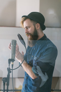 Hipster man singing in a studio