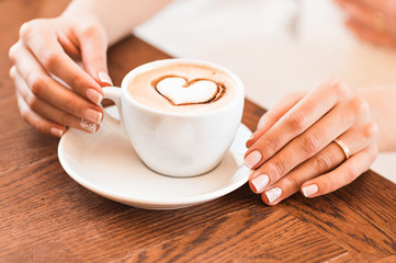 woman holding hot cup of coffee, with heart shape