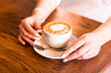 woman holding hot cup of coffee, with heart shape