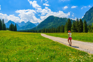 Fototapeta na wymiar Green summer landscape and young woman tourist walking on hiking trail in High Tatra Mountains, Slovakia