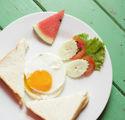 Fried egg with bread and vegetable with watermelon in plate