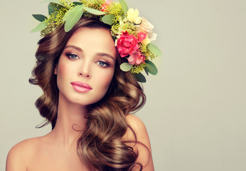 Beautiful woman model brunette with long curly hair floral wreath on the head . Spring girl . Summer fresh image .

