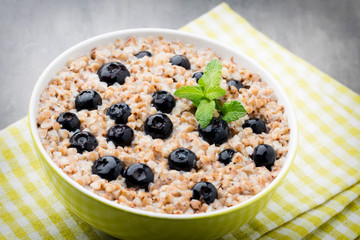 Buckwheat porridge in a bowl with mint leaves and blueberries.