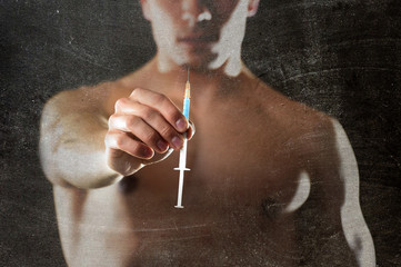 young athletic sportsman holding syringe in sport doping and cheat concept