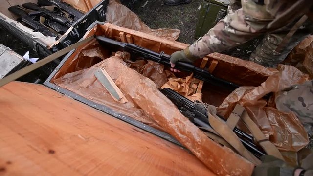 Soldier gets the weapon out of wooden military box. Top view.