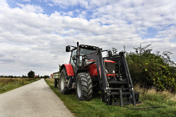 Traktor mit Anhaenger am Rand des Weges
