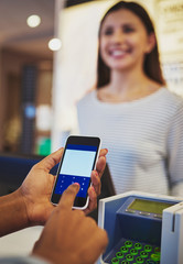 Close up on hands using phone for payment at store