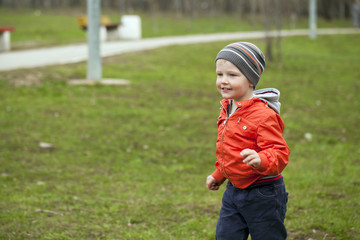 Fototapeta premium Baby boy in orange jaket and blue jeans