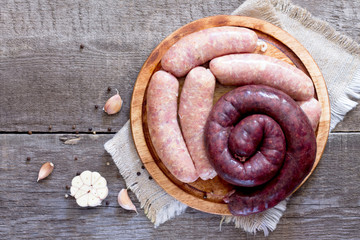Assortment of meat sausages on dark wooden background, top view.